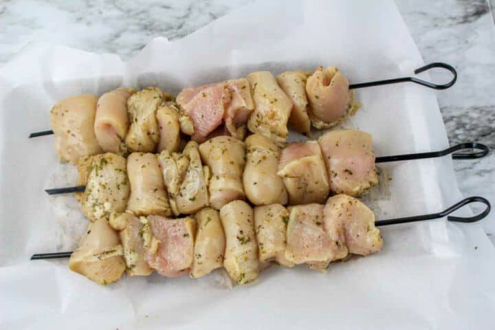 Marinated chicken pieces threaded onto metal skewers for grilled chicken kabobs.