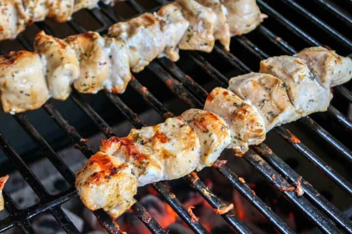 Chicken kabobs cooking on a grill.