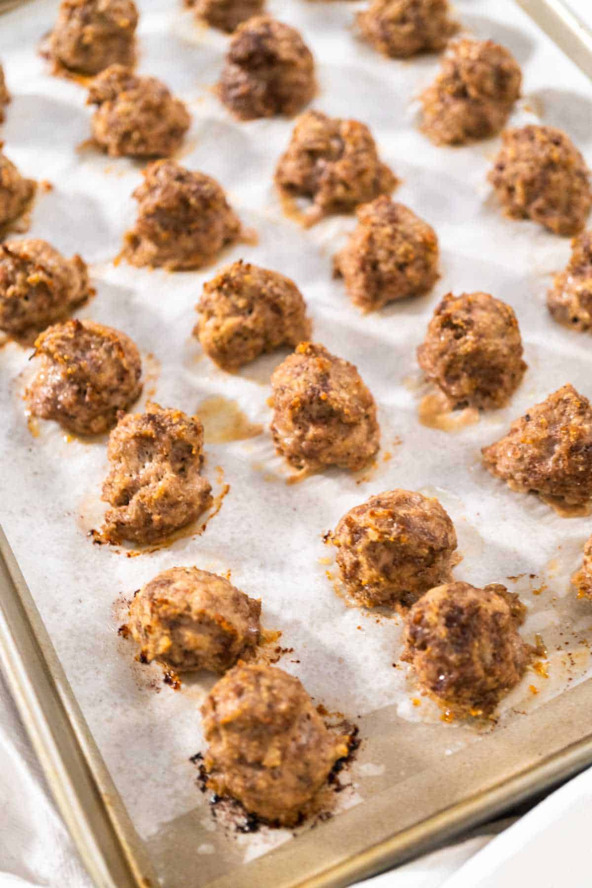 oven baked meat balls on a rimmed baking sheet.