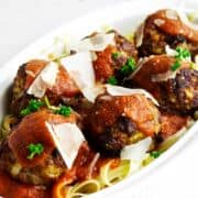 Casserole of wagyu meatballs on pasta and covered with marinara and cheese shavings.