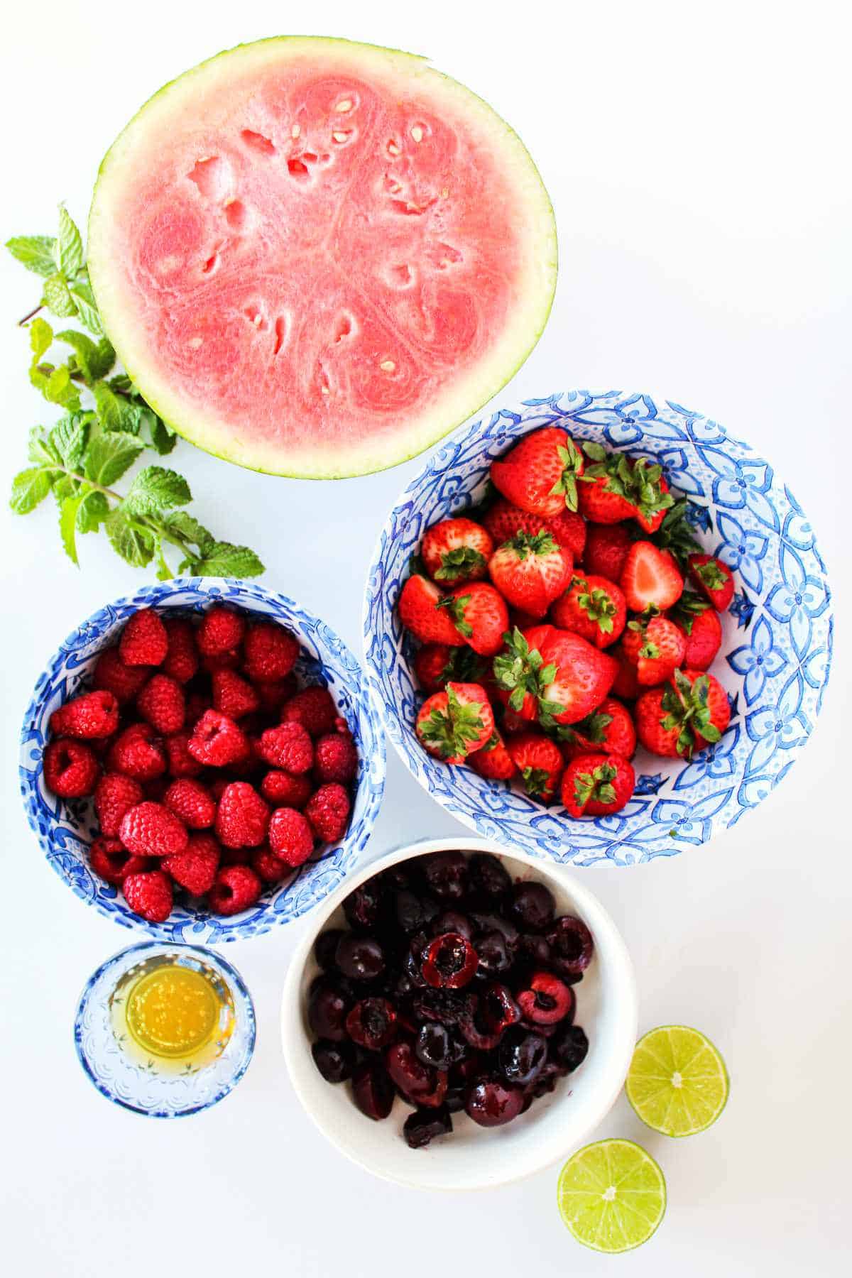 watermelon, raspberries, strawberries, cherries, and limes on a white background.