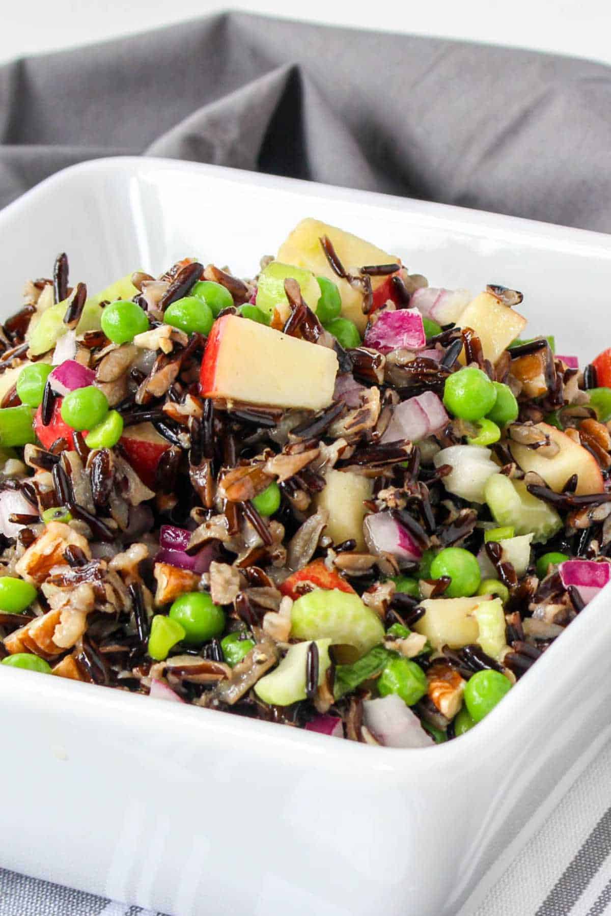 Serving bowl of wild rice salad on a white background.
