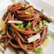 red wine spaghetti with parsley and Parmesan garnish.