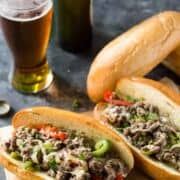 philly cheesesteaks with peppers and onions and a mug of beer.
