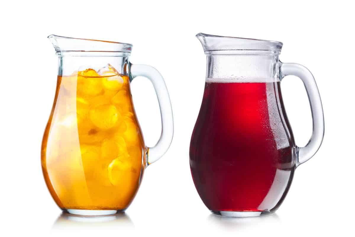 Two pitchers with transparent and opaque liquids of dark and light liquids.