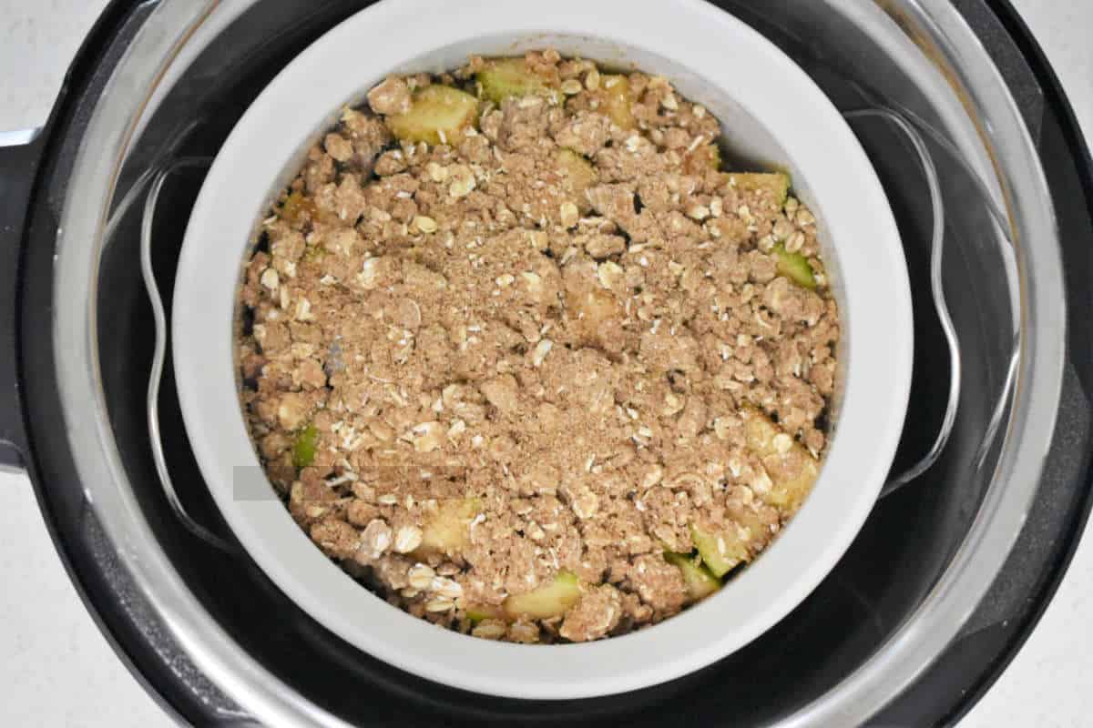small round casserole with uncooked cobbler or crisp in an Instant Pot, sitting on a trivet rack.