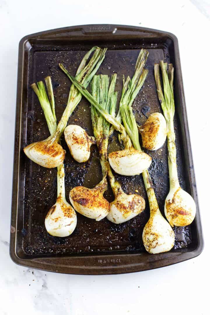 Roasted cebollitas on a sheet pan.