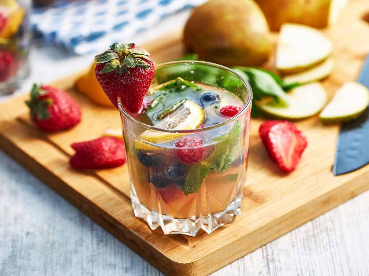garnishing a glass of punch with cut fruit.
