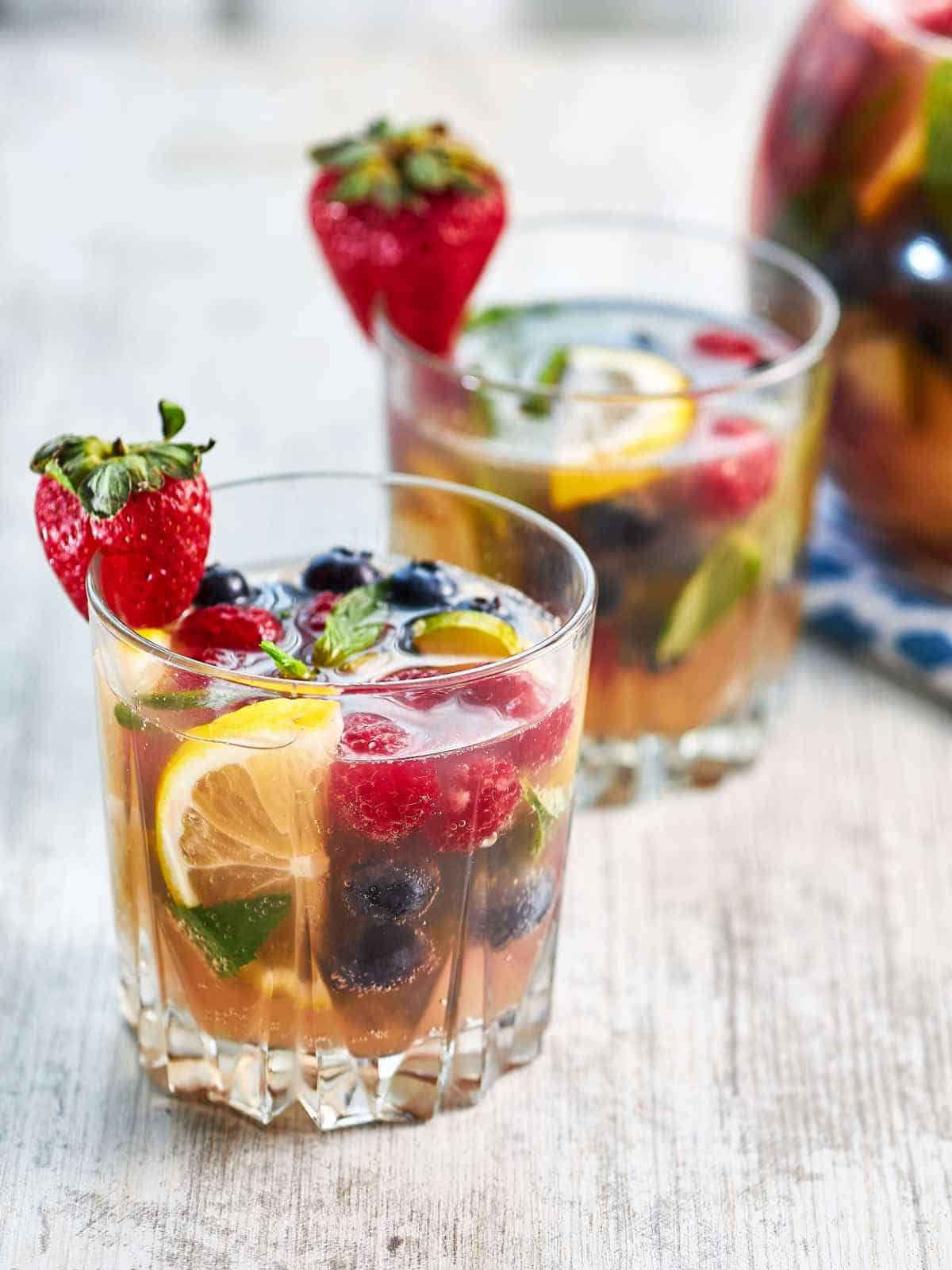 two glasses of blueberries, strawberries, sparkling wing and orange juice brunch white wine sangria.