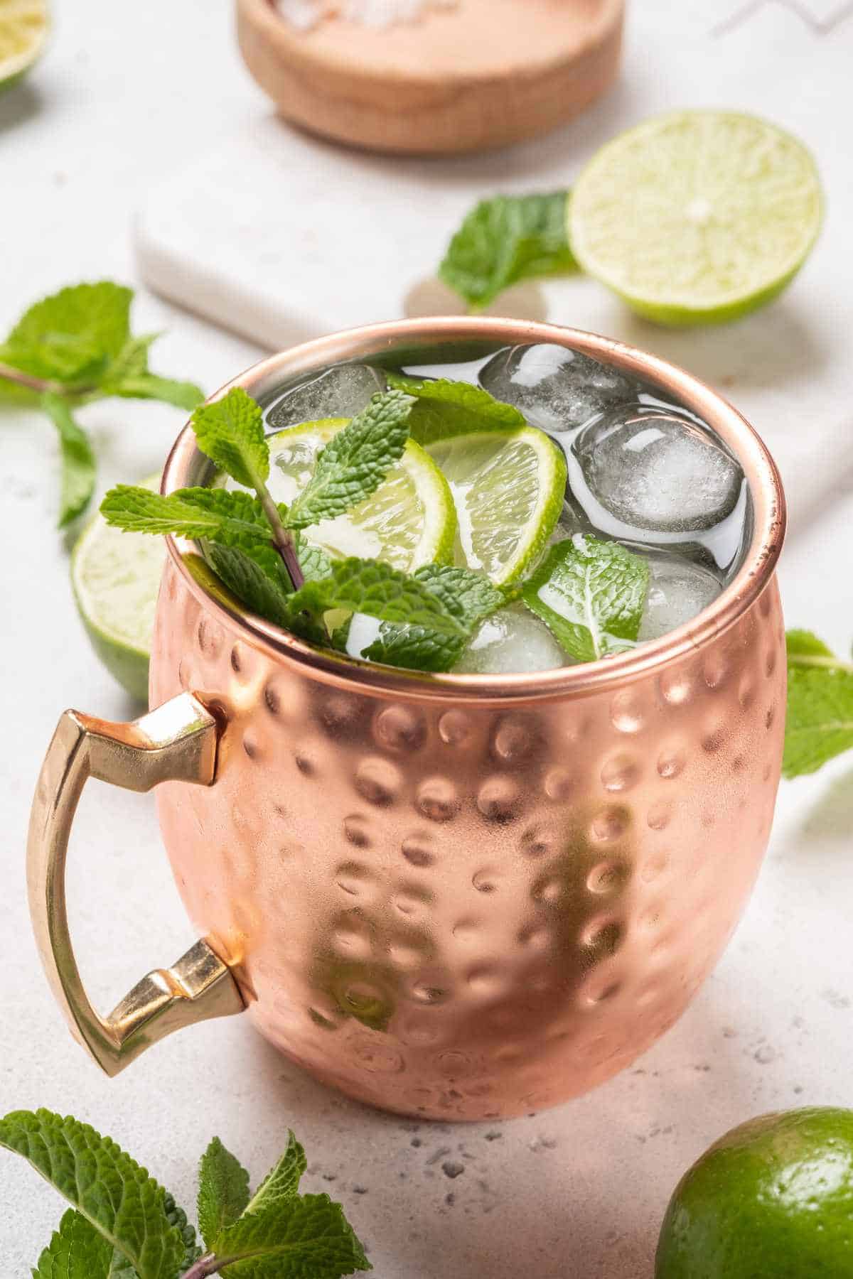 Moscow mule alcoholic cocktail in copper mug with lime, mint and cucumber.