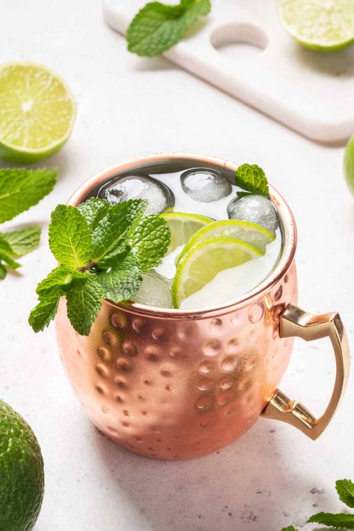 Moscow mule alcoholic cocktail in copper mug with lime, mint and cucumber.