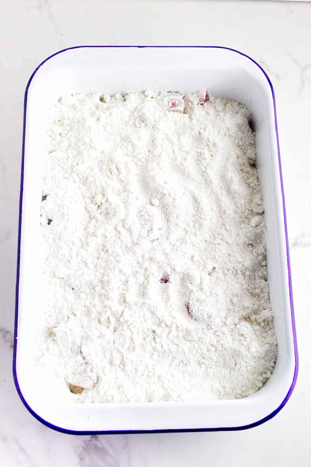 cake mix sprinkled over cut fruit in a baking dish.