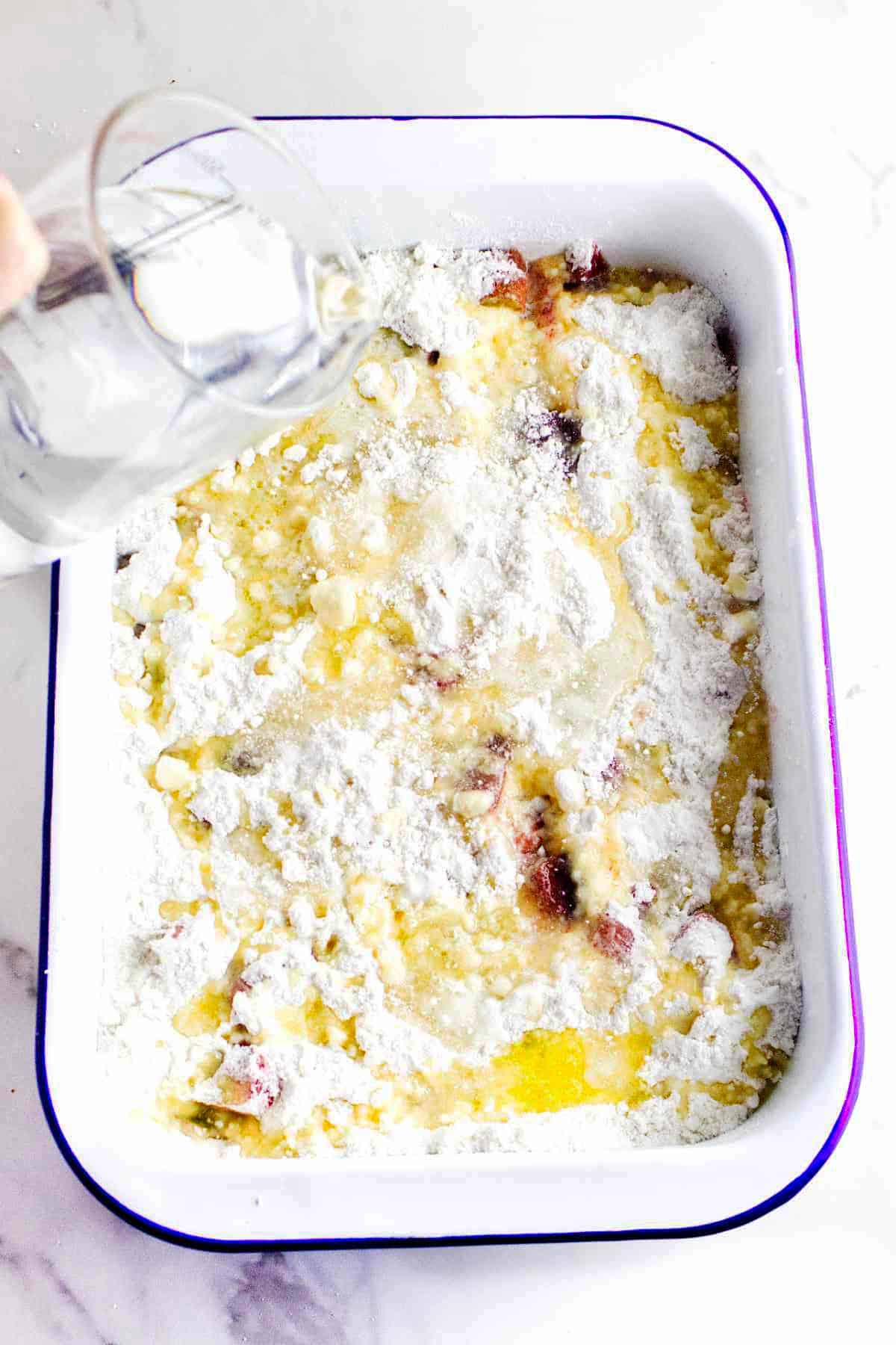 Butter and water drizzled over the cake mix in a baking dish.