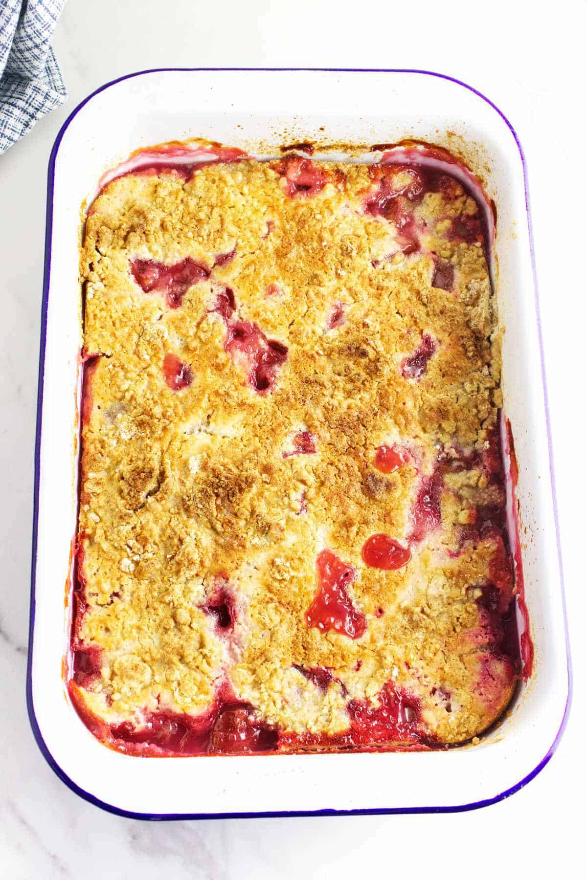 baking dish with bubbly fruit ebbing up in the cracks of the crust.