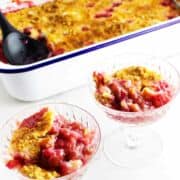pan of Rhubarb dump cake in the background with servings in two parfait glasses.