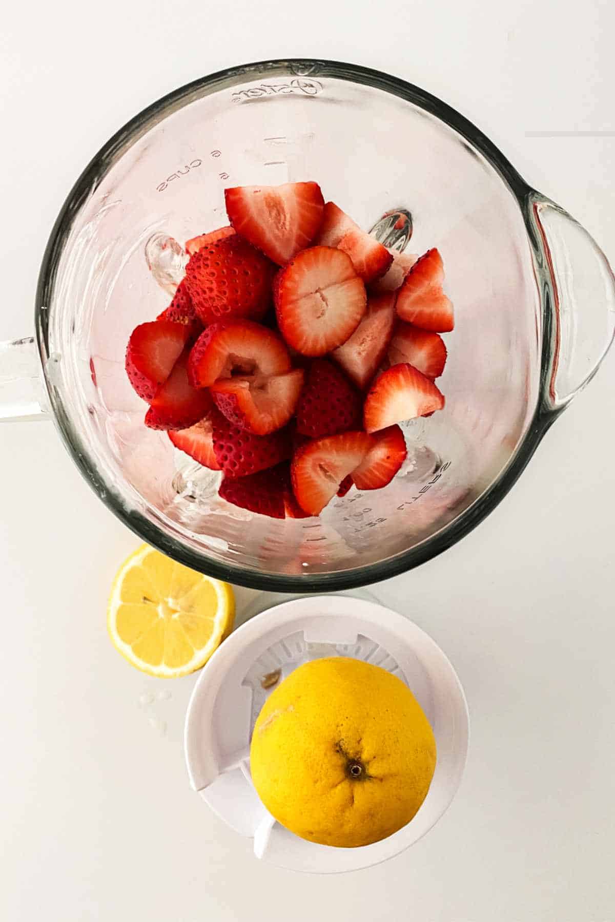 blender with berries and a squeezed lemon nearby.