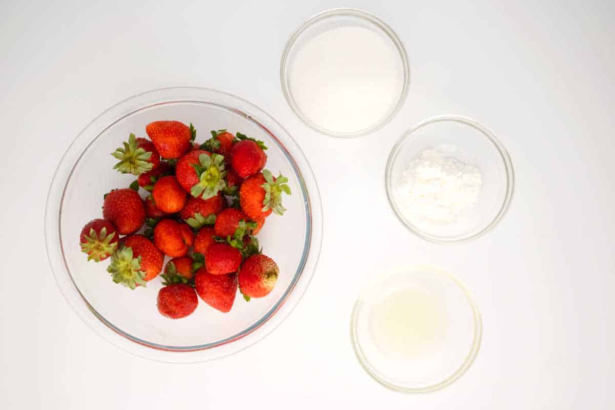 bowl of fresh strawberries, bowls of sugar, cornstarch, and lemon juice.