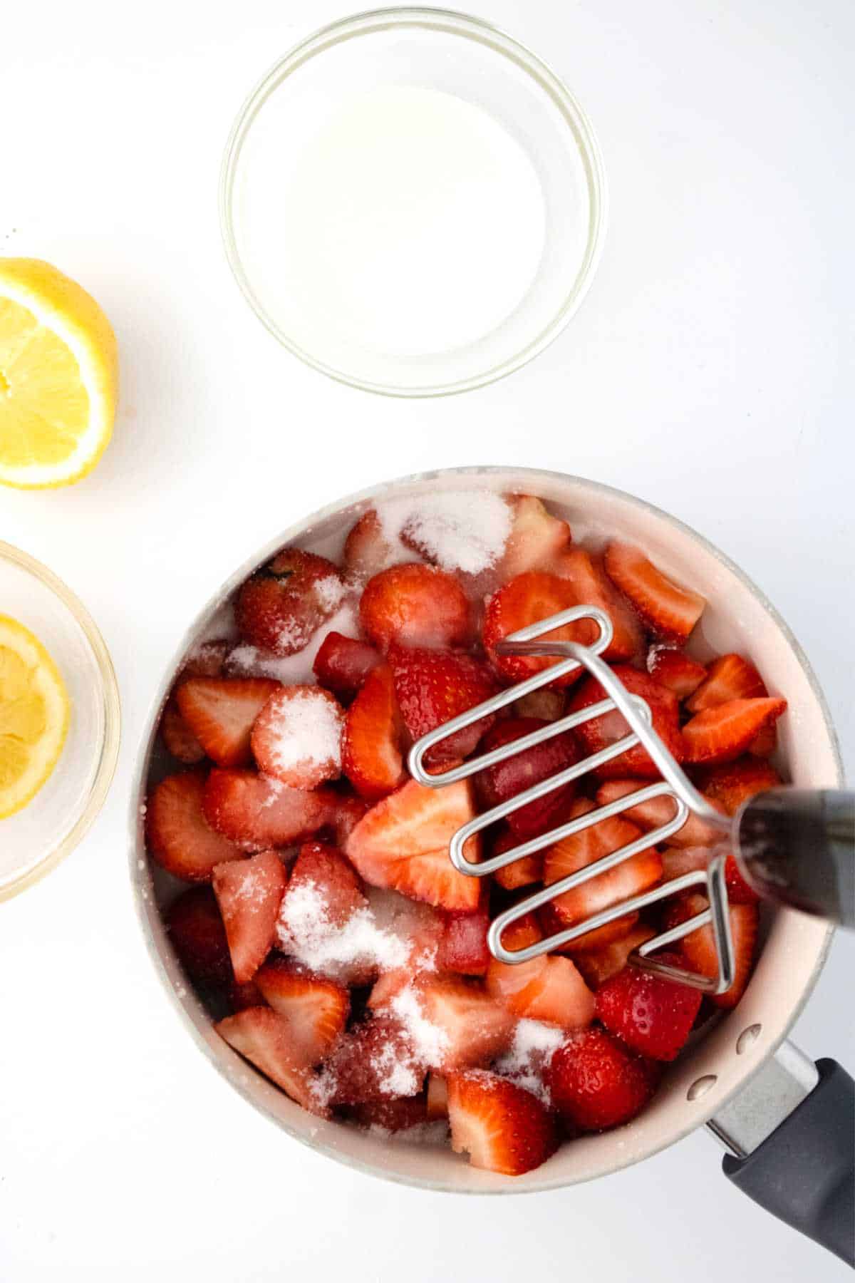 mashing tool smashing strawberries in a sauce pan.