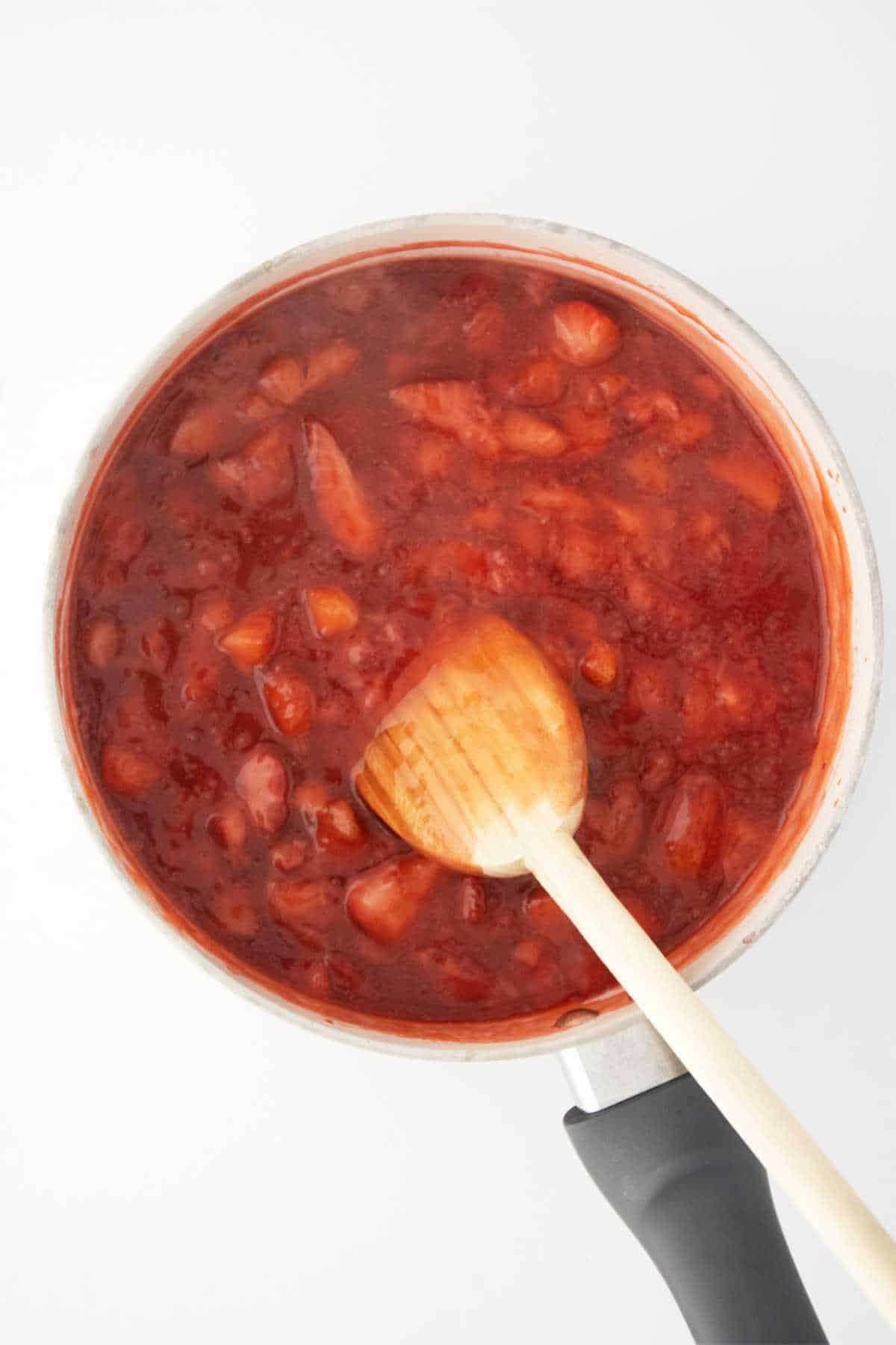 thickened strawberry jam cooking in a sauce pan.