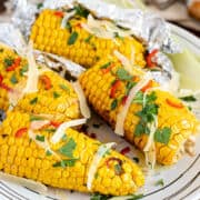 Smoked ears of corn garnished with chopped parsley and Parmesan cheese.