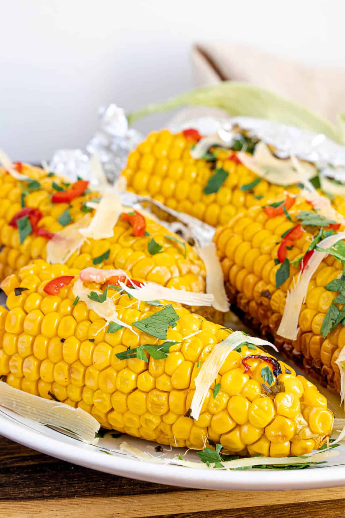 corn on the cob on traeger garnished with chopped parsley and Parmesan cheese.