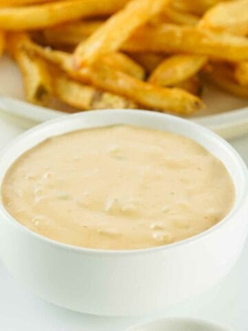 animal sauce in a bowl with fries in the background.