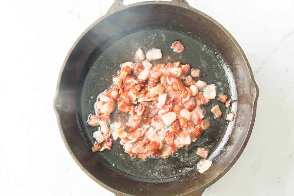 diced bacon crisping in a skillet.
