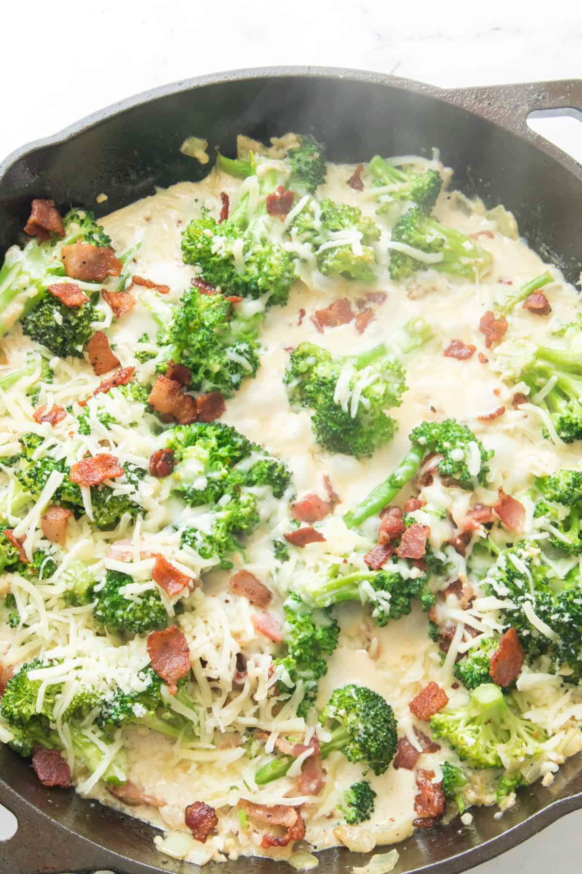 creamy broccoli and bacon alfredo in a cast iron skillet.