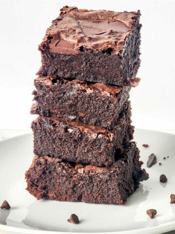 four brownies stacked on a plate.