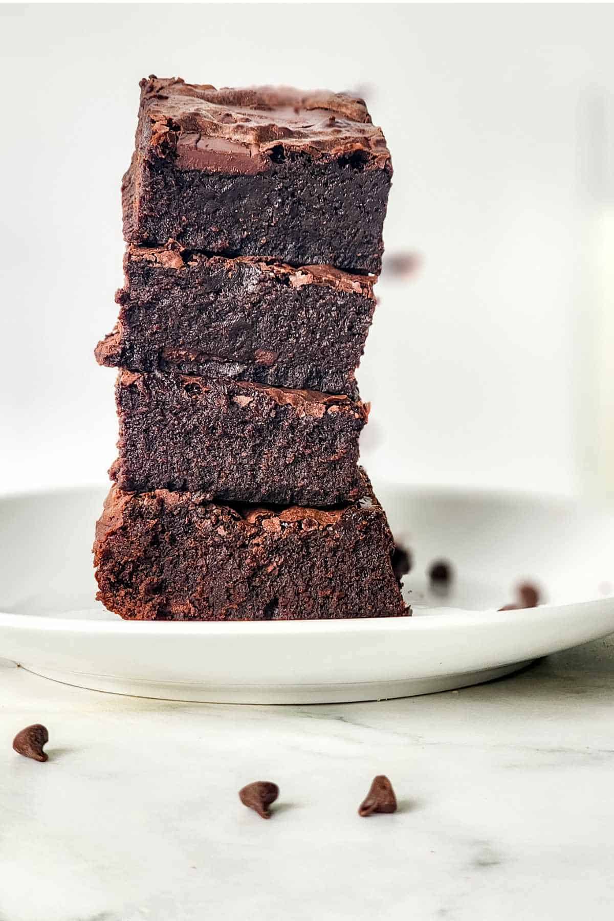 four sweetened condensed milk brownies stacked on a plate.