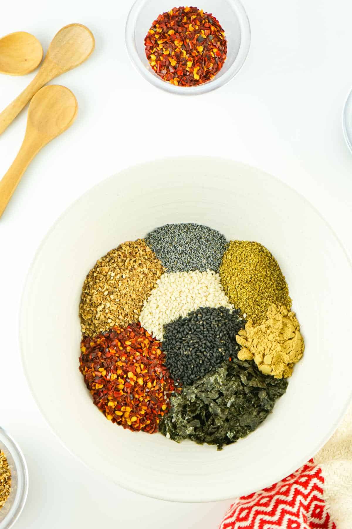 bowl of spices arranged by color, on a white background.