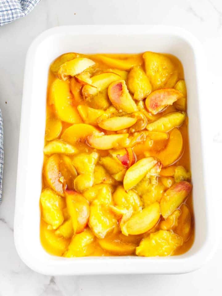 fresh peaches cut up in a baking dish.