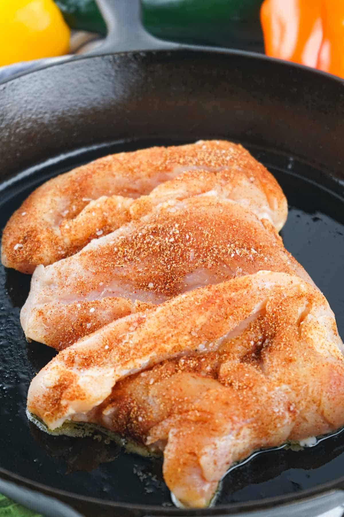 seasoned chicken breasts in a cast iron skillet.