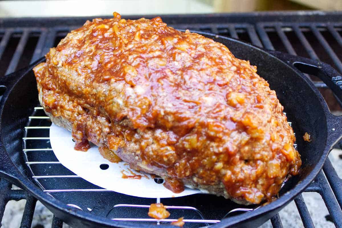 uncooked meatloaf in a cast iron pan on a Traeger smoker.