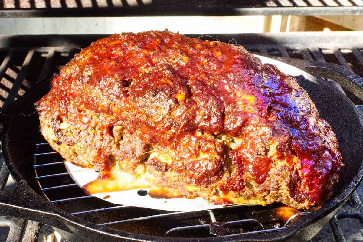 barbecued smoked meatloaf in a cast iron skillet on a Traeger smoker grill.