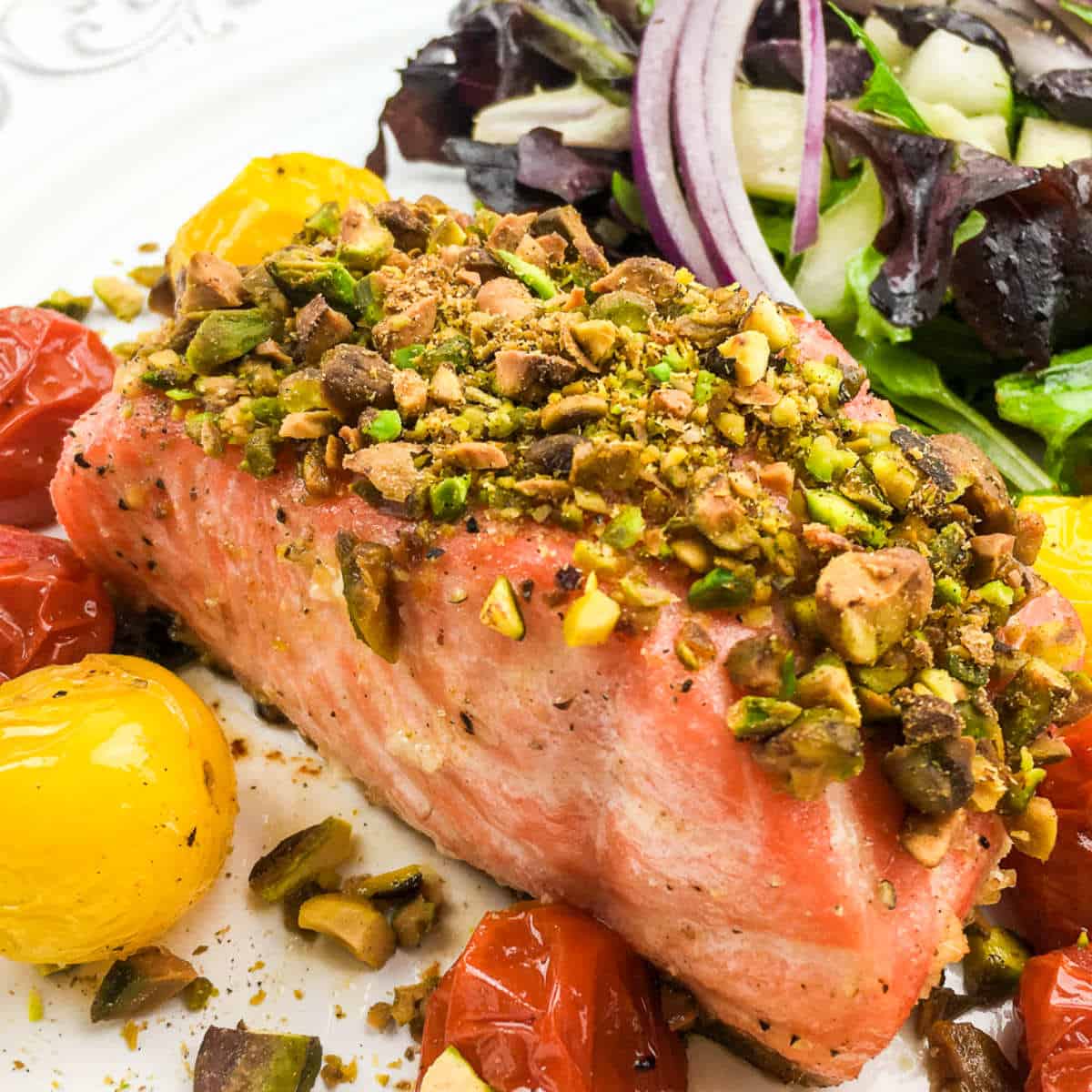 plate with pistachio crusted salmon and blistered tomatoes.
