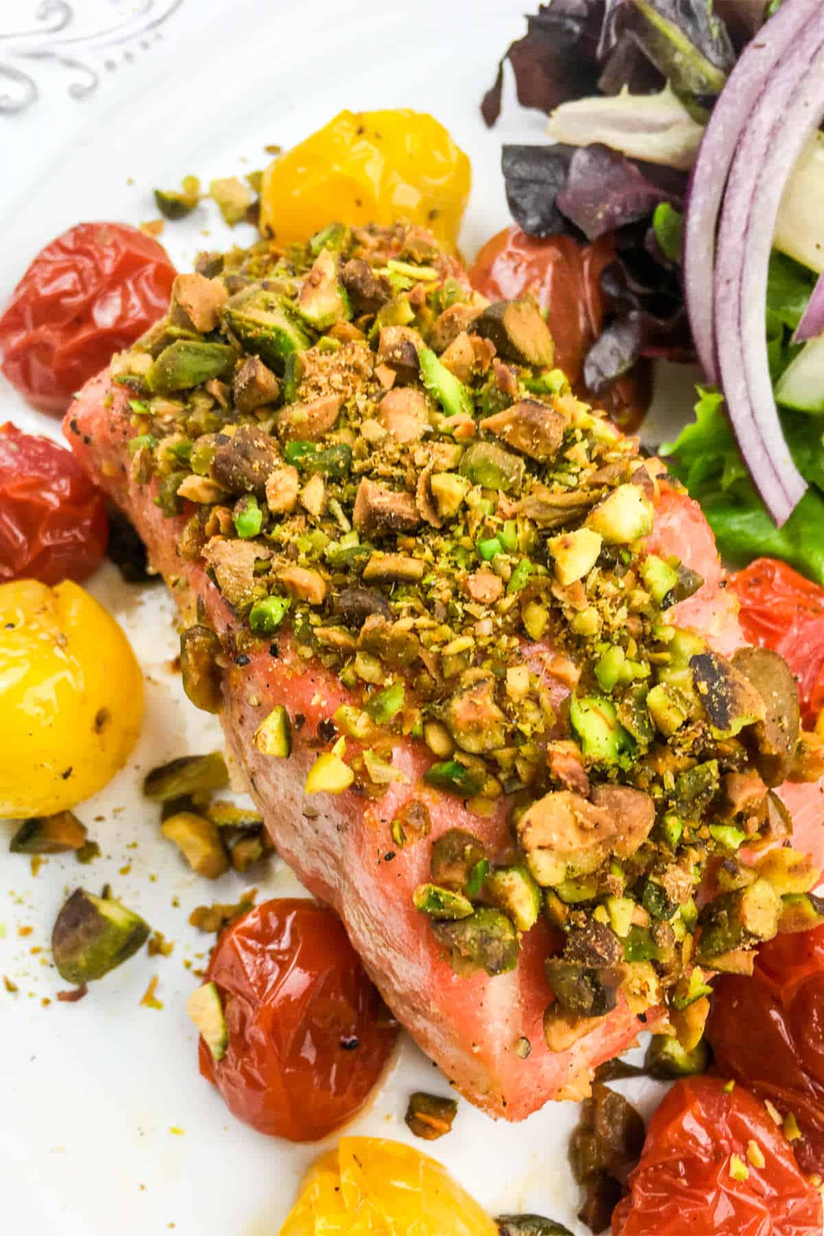 plate with pistachio crusted salmon and blistered tomatoes.