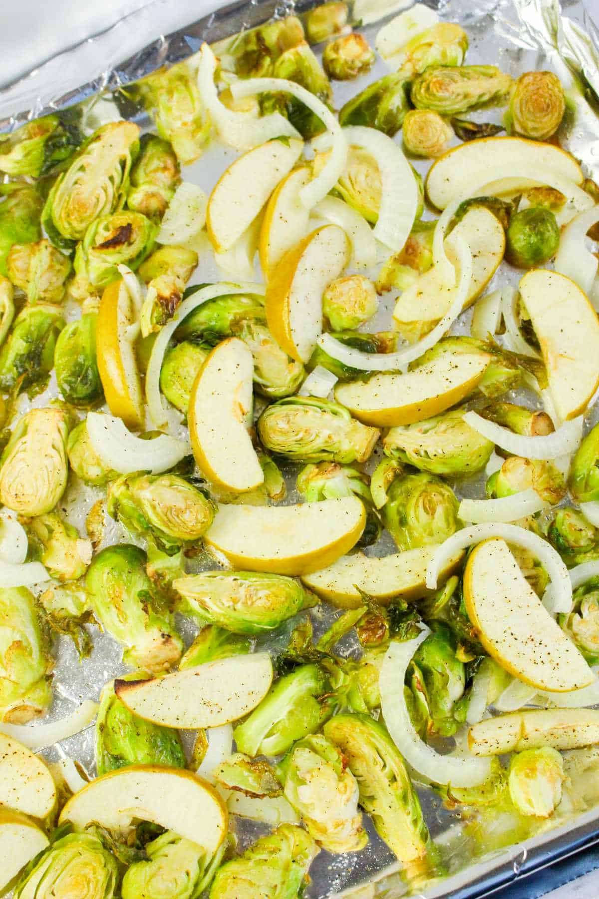 sheet pan with roasted brussel sprouts and sliced granny smith apples.