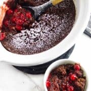 bowl of black forest dump cake with crockpot full nearby.