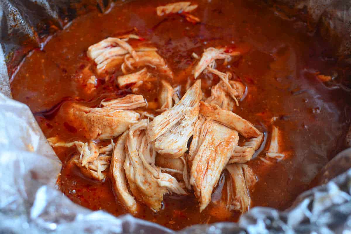 shredded meat added to slow cooker with sauce.