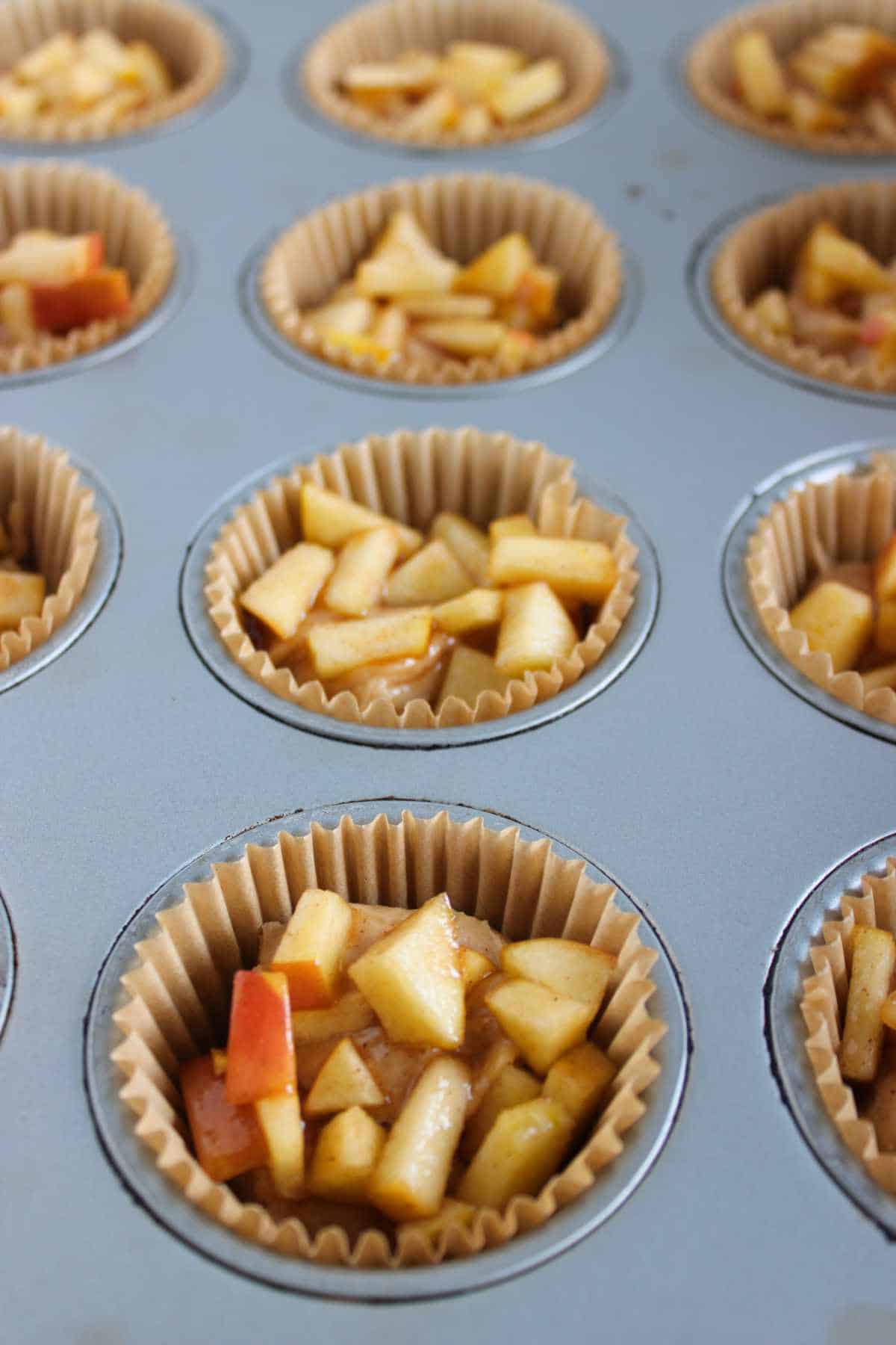 apple caramel on top of cake batter in muffin tin.