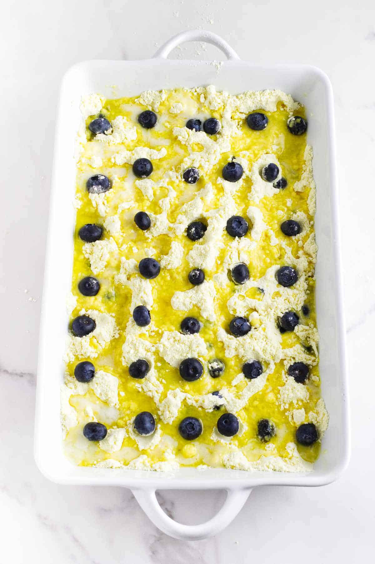melted butter drizzled over cake mix and fresh blueberries dotting the top.