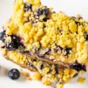 two blueberry lemon bars stacked on a plate.