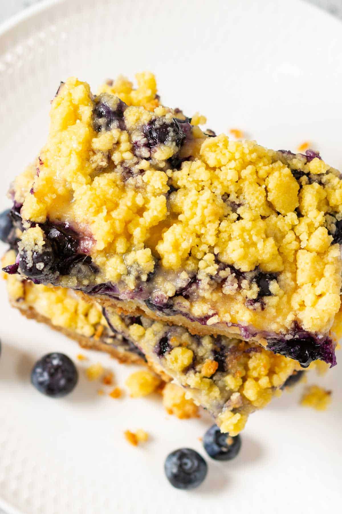 two blueberry lemon dump cake bars stacked on a plate.