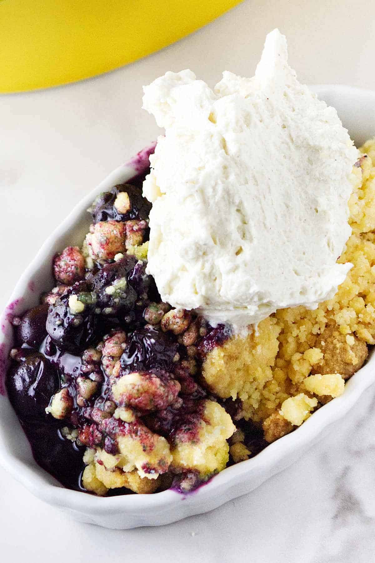 serving of blueberry cobbler with whipped cream on top.