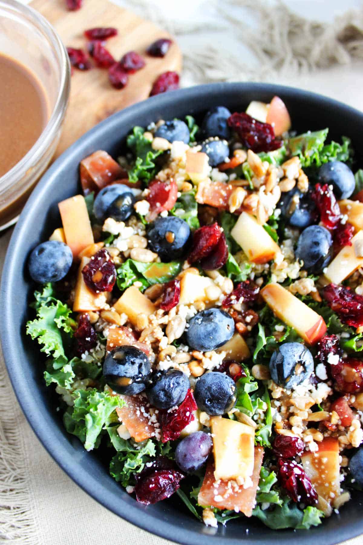 blueberry kale crunch salad in a bowl with feta cheese crumbled on top.