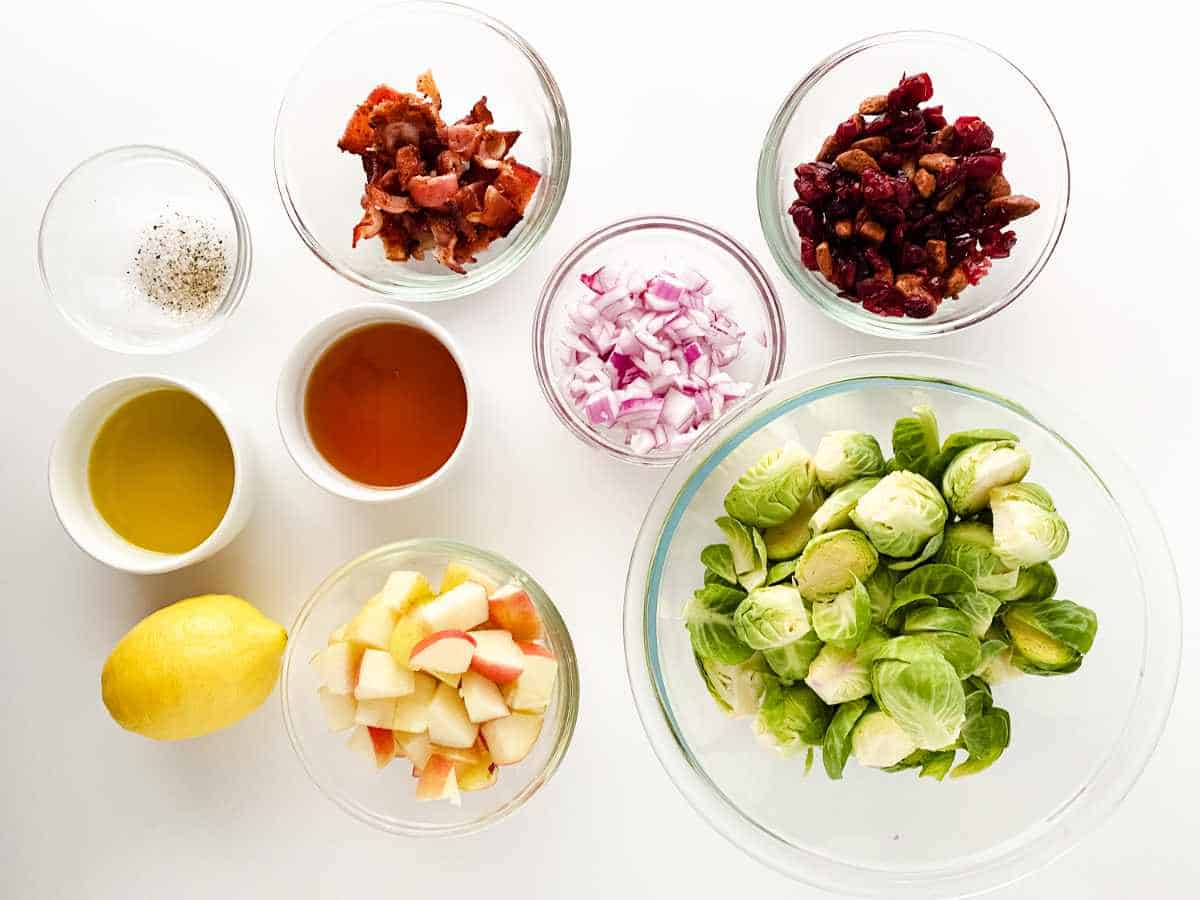 bowls of chopped apple, crisp bacon, cranberries, and other salad ingredients.