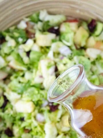 pouring salad dressing on a salad.