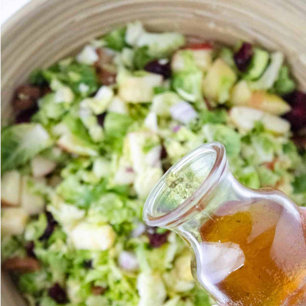 pouring salad dressing on a salad.
