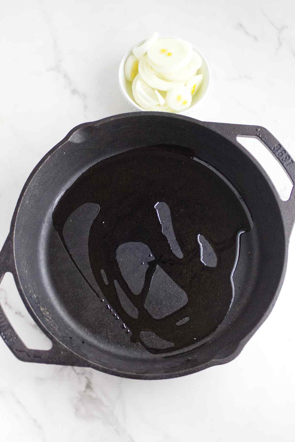 skillet with oil and sliced onions nearby.